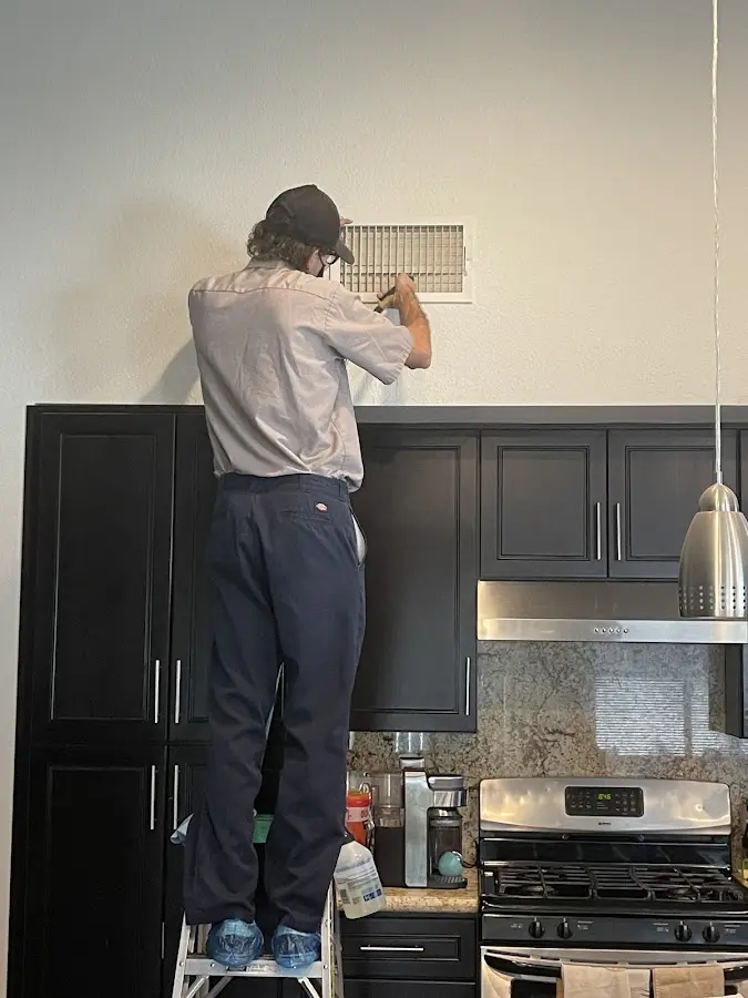 Technician inspecting an air vent during HVAC service in Vernon